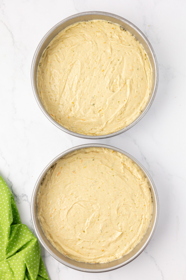 overhead view of citrus cake batter in two round cake pans ready to go into the oven