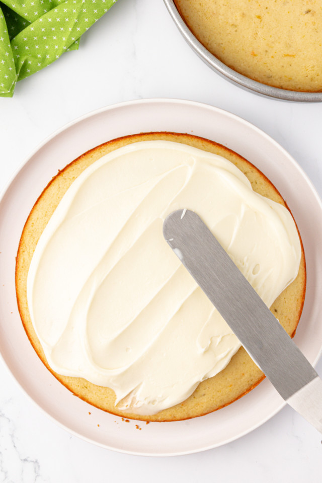 overhead view of tequila-lime frosting being spread on top of citrus cake