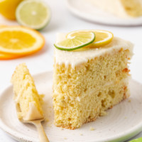 a slice of citrus cake with tequila lime frosting on a plate with a bite on a fork