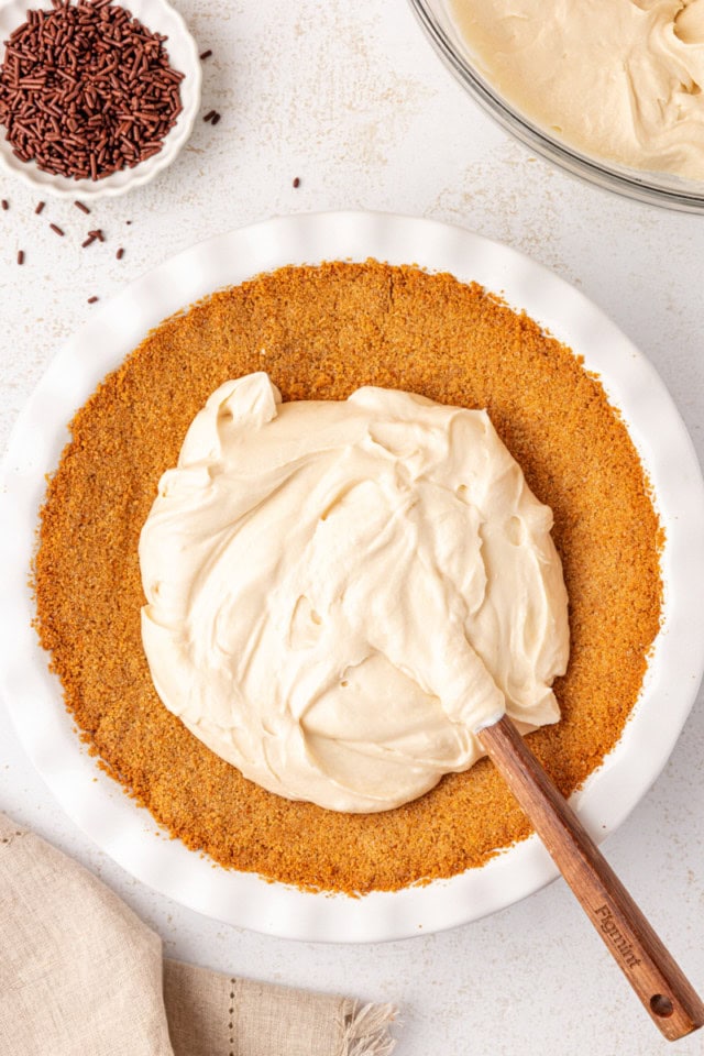 overhead view of Bailey's cheesecake filling spread in a graham cracker crust in a white pie plate