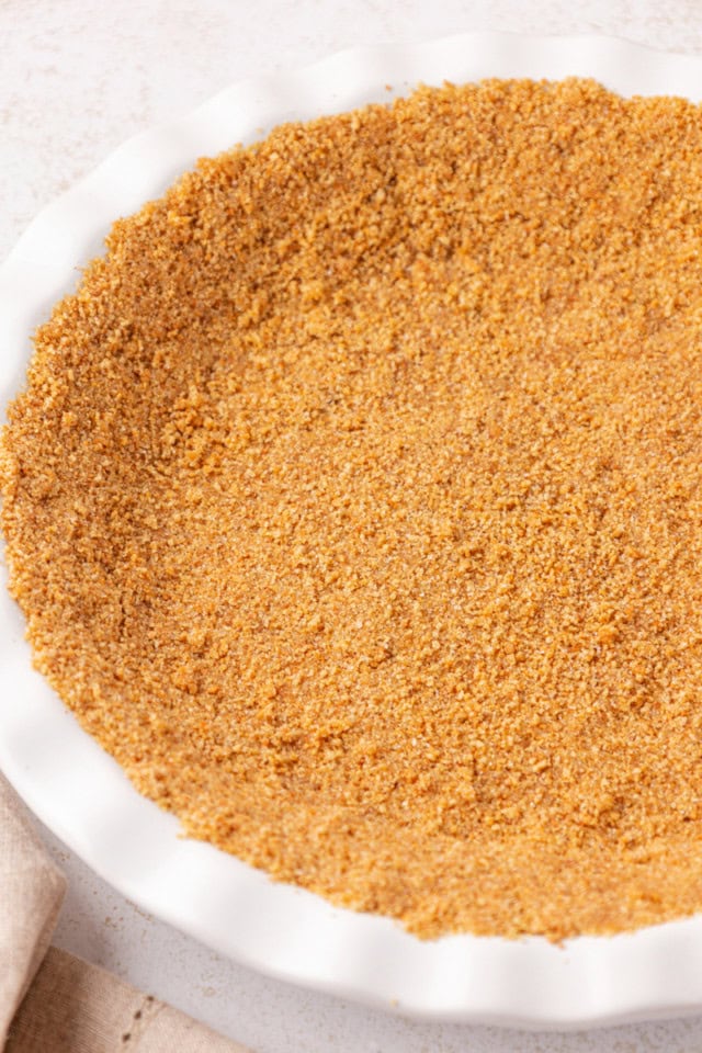 overhead view of graham cracker crust pressed into a white pie plate