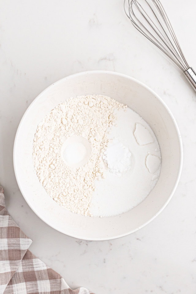 overhead view of flour, sugar, baking soda, and salt in a white mixing bowl