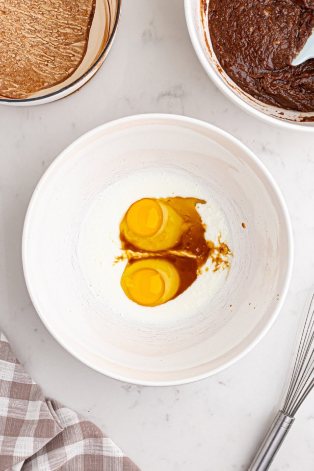 overhead view of eggs, buttermilk, and vanilla extract in a white mixing bowl