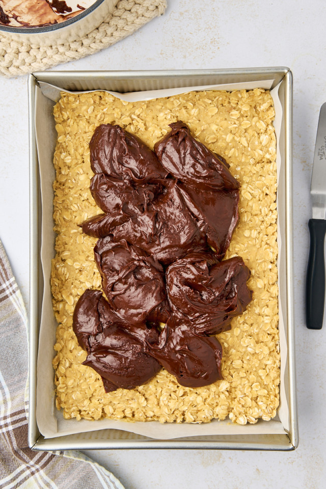 overhead view of chocolate mixture on top of the bottom layer of revel bars in a 9x13 pan