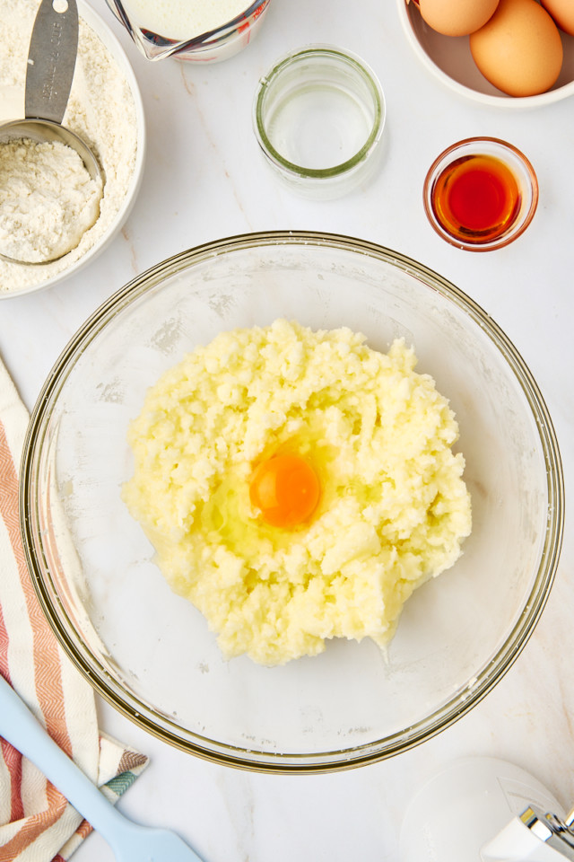 overhead view of egg added to creamed butter and sugar in a mixing bowl