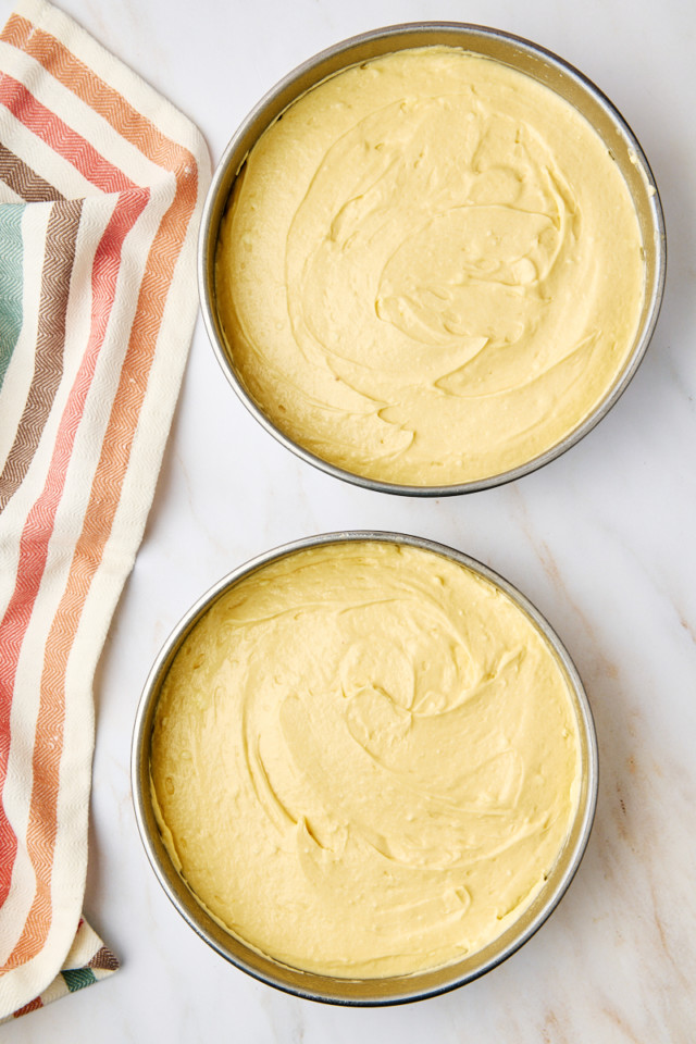 overhead view of yellow cake batter in two round cake pans ready to go into the oven