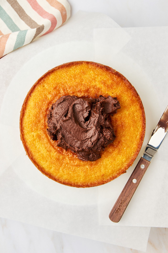 overhead view of chocolate frosting on top of a yellow cake layer