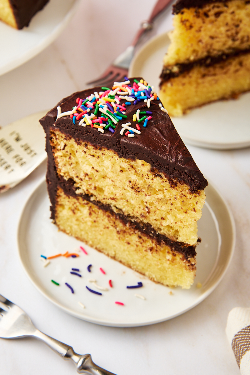 a slice of yellow cake with chocolate frosting on a white plate