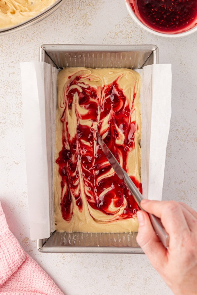 overhead view of berry preserves being swirled into cake batter