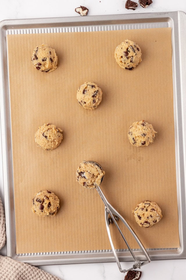 overhead view of scooped Oreo chocolate chip cookies on a parchment-lined baking sheet ready to go into the oven