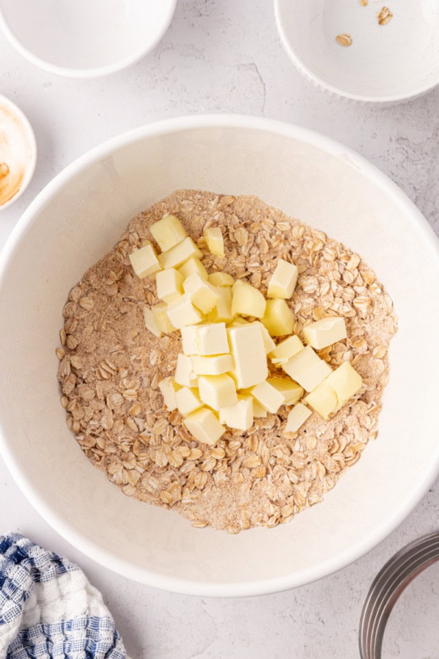 overhead view of butter added to dry crisp topping ingredients in a white bowl