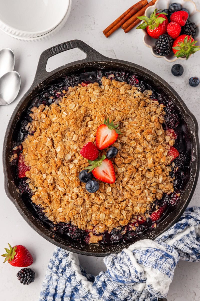 overhead view of berry crisp in a cast-iron skillet garnished with a few berries