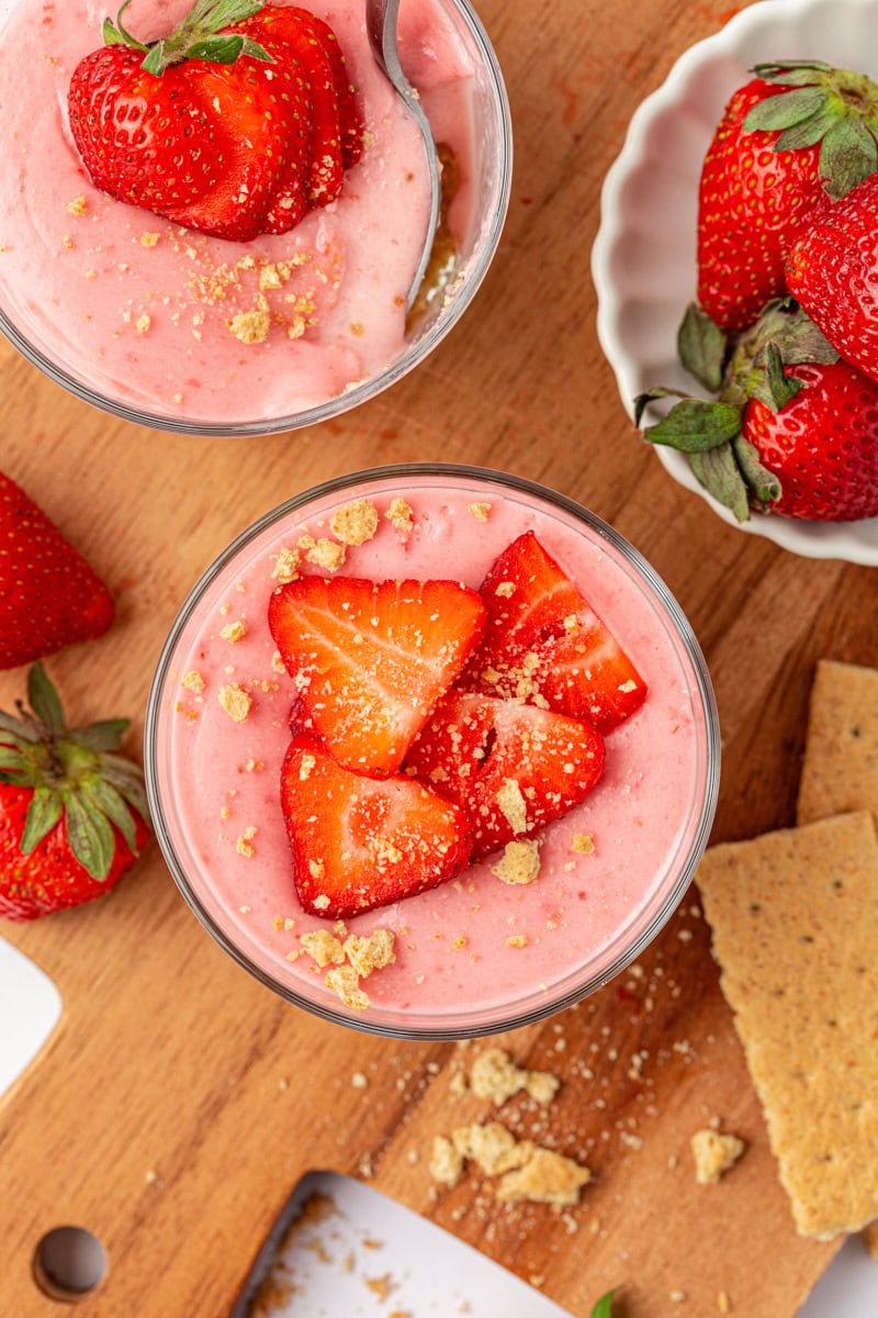 overhead view of two strawberry no-bake cheesecakes topped with fresh strawberry slices and graham cracker crumbs