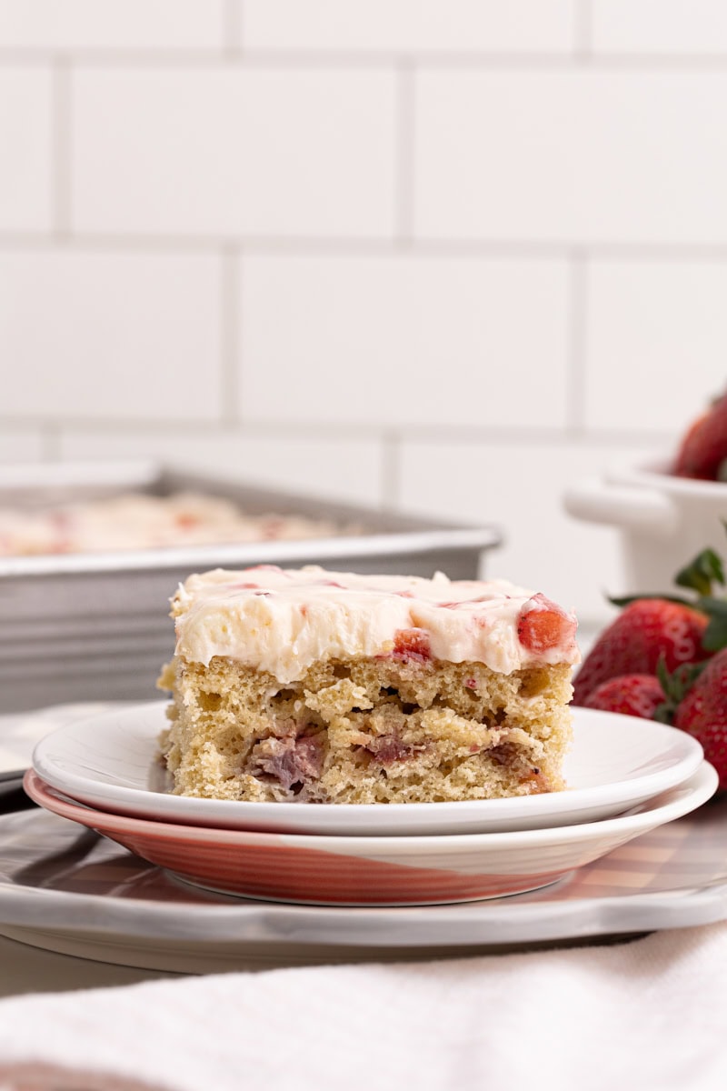 a slice of strawberry sheet cake on a small stack of plates