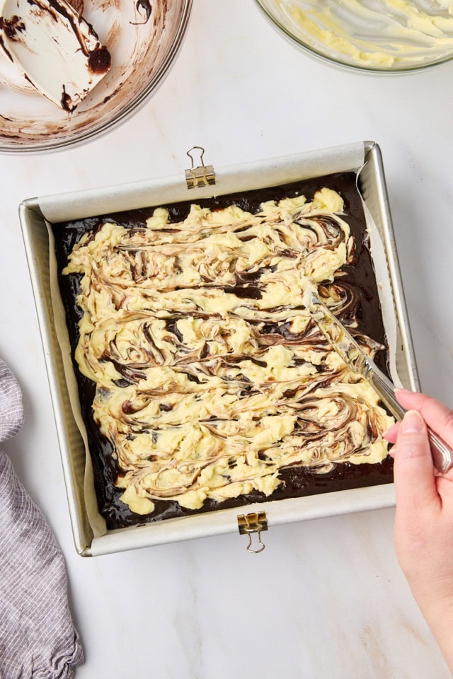 overhead view of coconut cream cheese mixture being swirled into brownie batter