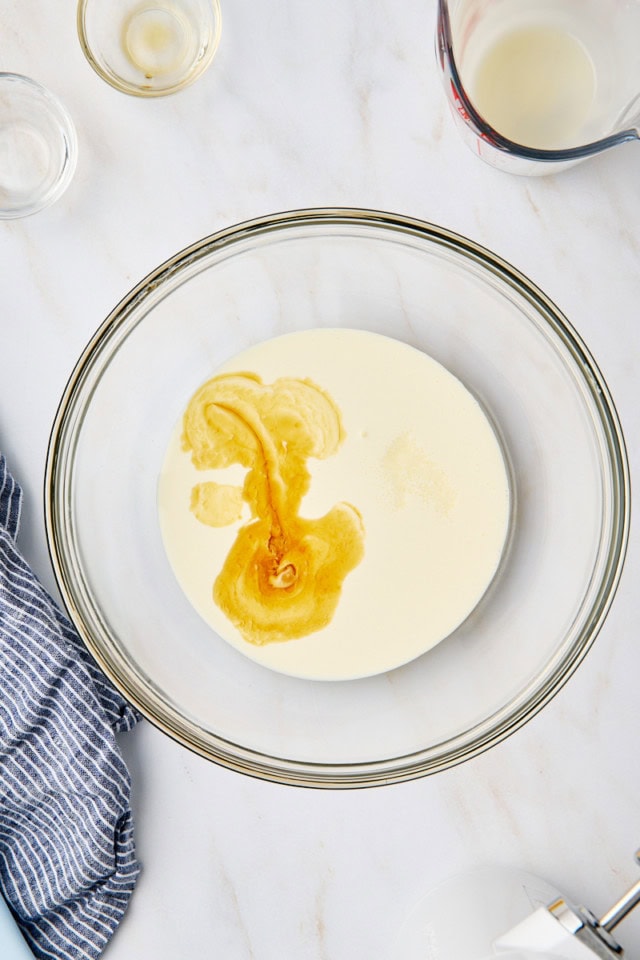 overhead view of heavy cream, vanilla extract, and salt in a glass mixing bowl