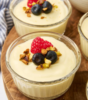 two servings of white chocolate mousse in clear ramekins on a wooden board