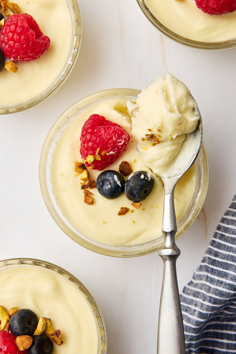 overhead view of a spoonful of white chocolate mousse resting on a ramekin with the remaining serving of mousse; more ramekins of mousse partially visible surrounding