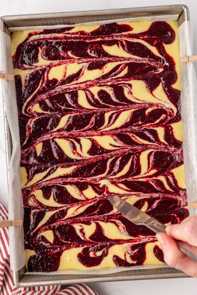 overhead view of cherry topping being swirled into cheesecake filling
