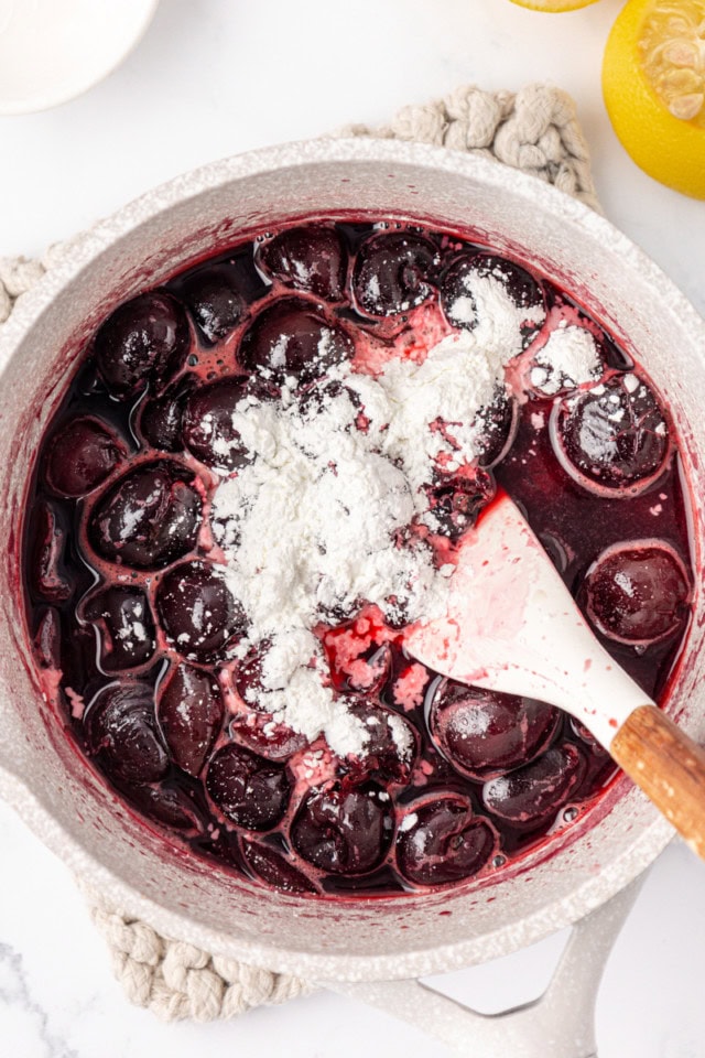 overhead view of cornstarch and lemon juice added to partially cooked cherry topping