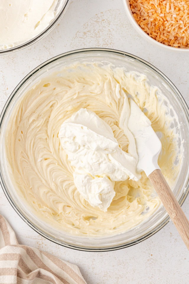 overhead view of whipped cream added to beaten cream cheese mixture for no-bake coconut cheesecake