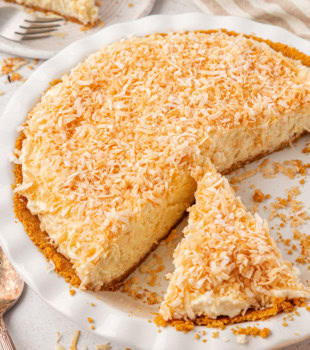 no-bake coconut cheesecake in a white pie pan with two slices partially visible around it