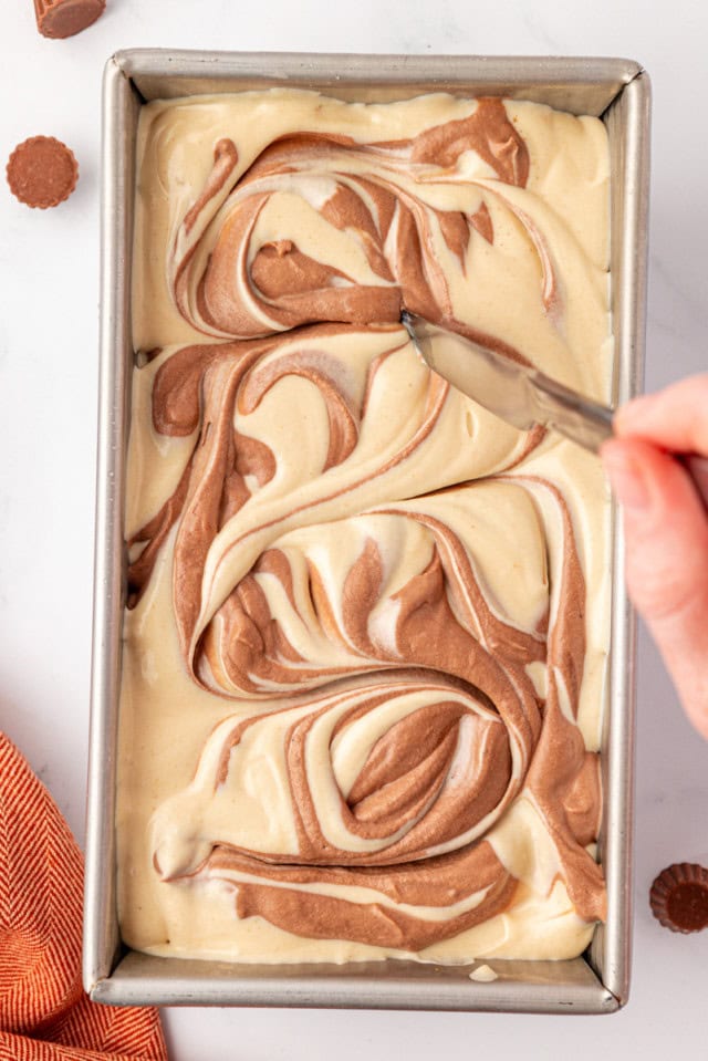 overhead view of a knife swirling chocolate and peanut butter ice creams together