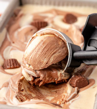 no-churn chocolate peanut butter ice cream in an ice cream scoop resting on the remaining ice cream in a metal loaf pan
