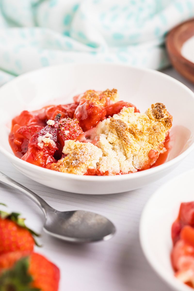 strawberry cobbler in a white bowl with a spoon next to it