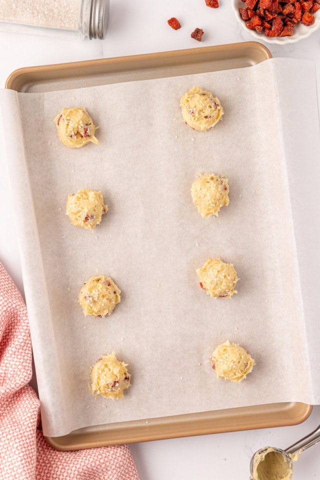 overhead view of strawberry cream cheese cookie dough portioned onto a parchment-lined baking sheet