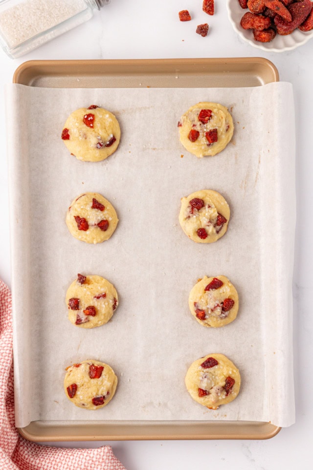 overhead view of freshly baked strawberry cream cheese cookies on a parchment-lined baking sheet