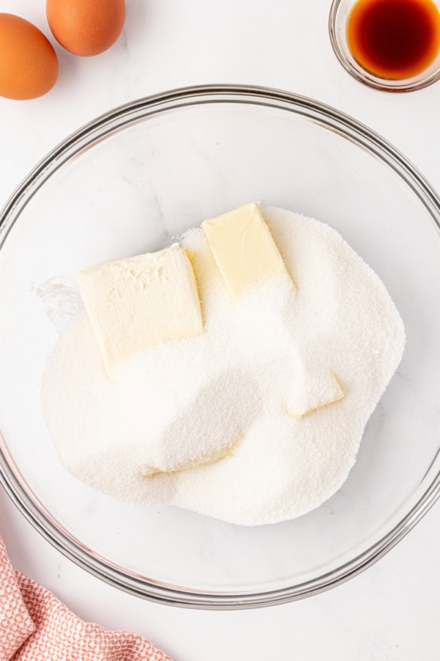 overhead view of butter, cream cheese, and sugar in a glass mixing bowl