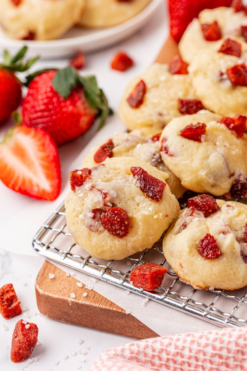 strawberry cream cheese cookies on a wire rack with more cookies and fresh strawberries in the background