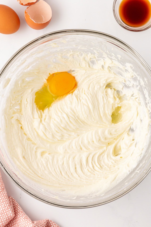 overhead view of egg added to creamed butter, cream cheese, and sugar