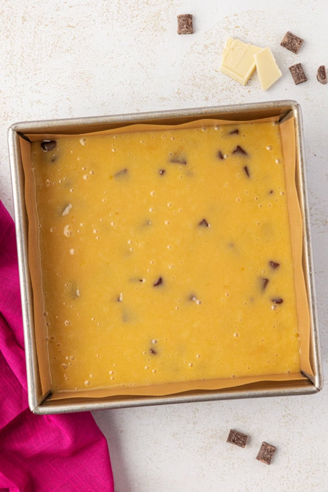 overhead view of white chocolate brownie batter in a square baking pan ready to go into the oven