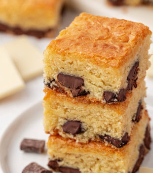 a stack of three white chocolate brownies on a white plate