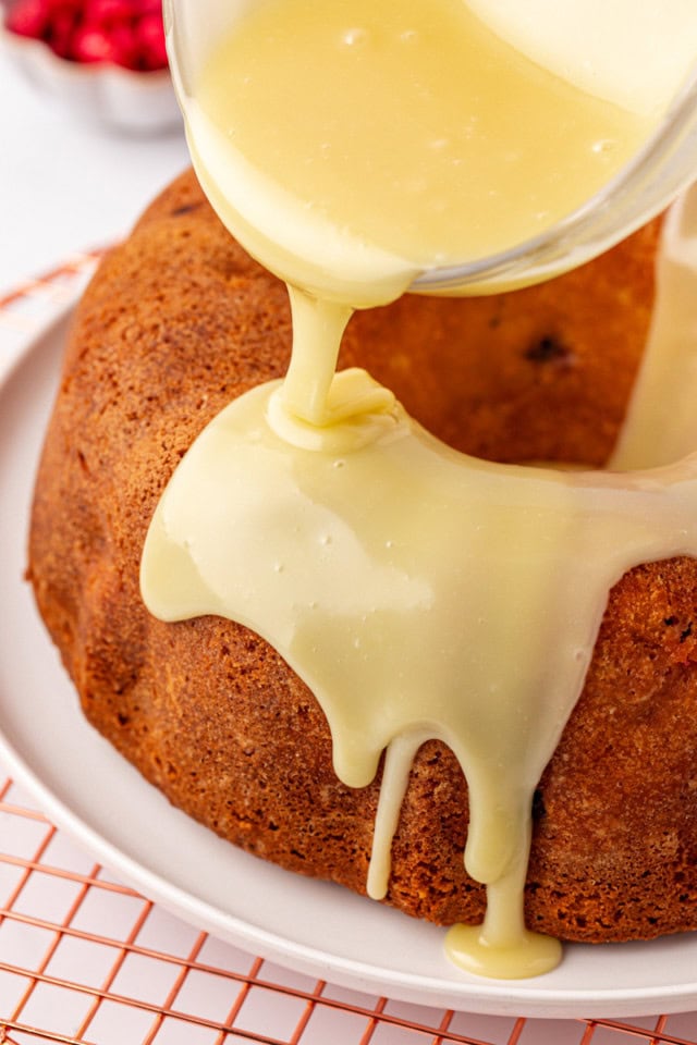 white chocolate ganache being poured over raspberry Bundt cake