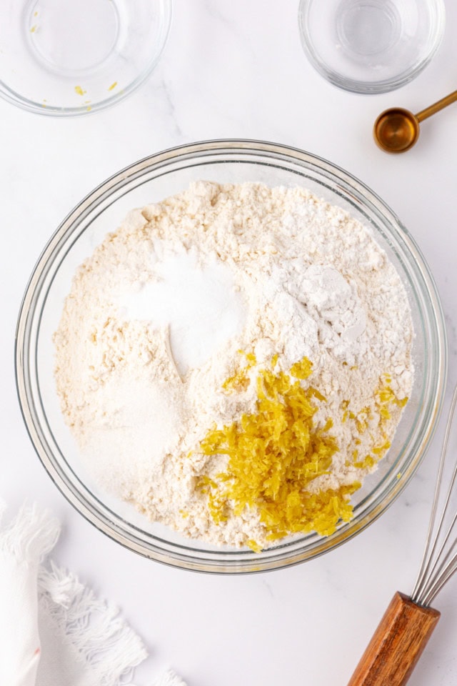 overhead flour, baking powder, baking soda, salt, and lemon zest in a glass mixing bowl