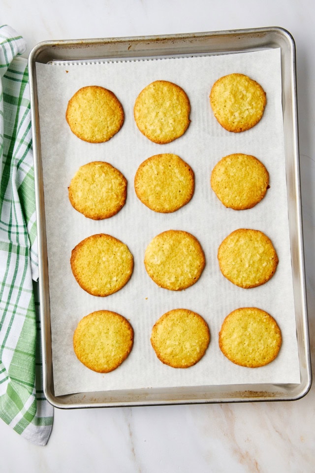 overhead view of freshly baked coconut lime cookies on a parchment-lined baking sheet