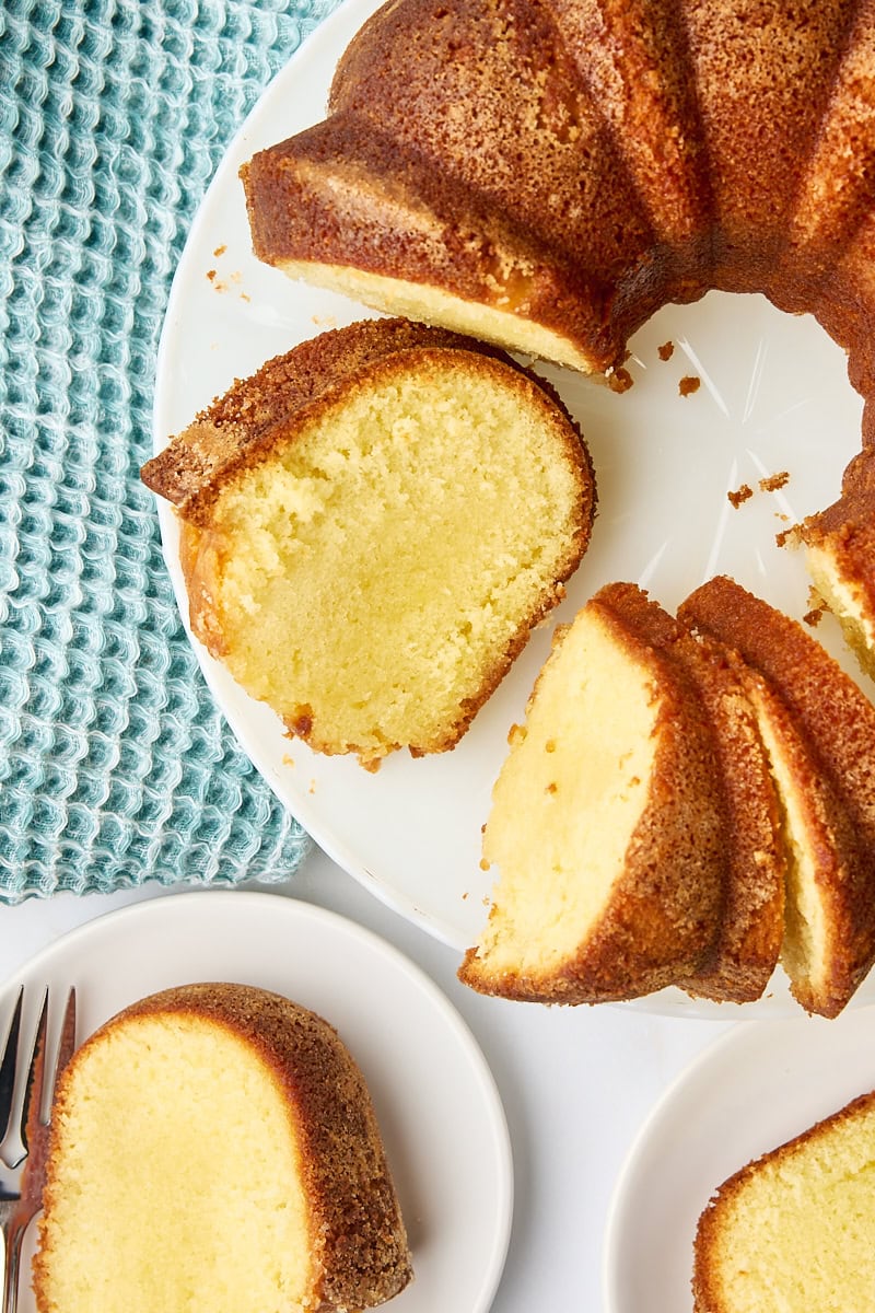 overhead view of partially sliced five flavor pound cake on a cake stand with two slices on plates nearby