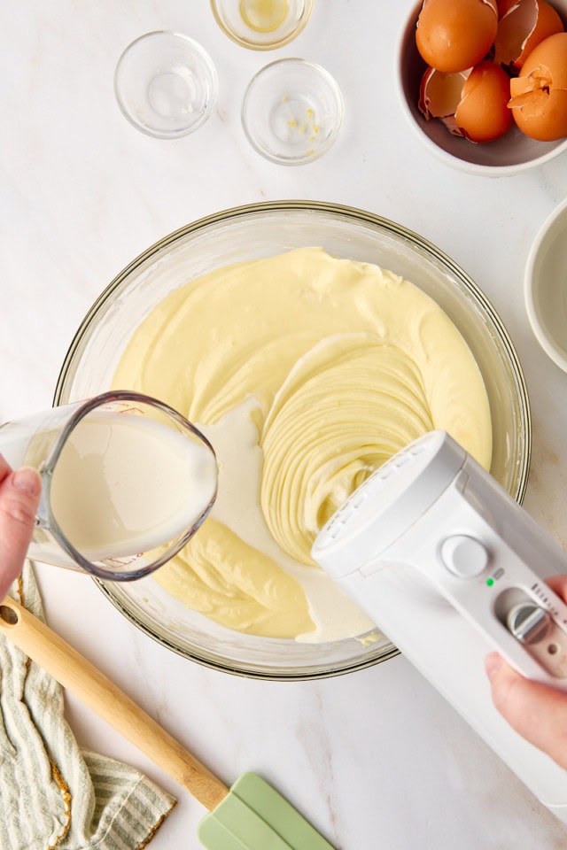 overhead view of heavy cream being poured and mixed into cheesecake batter