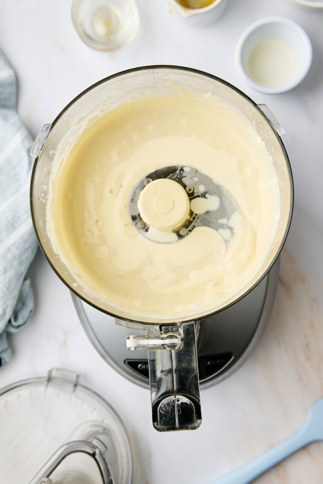 overhead view of heavy cream added to ricotta mousse mixture in the bowl of a food processor