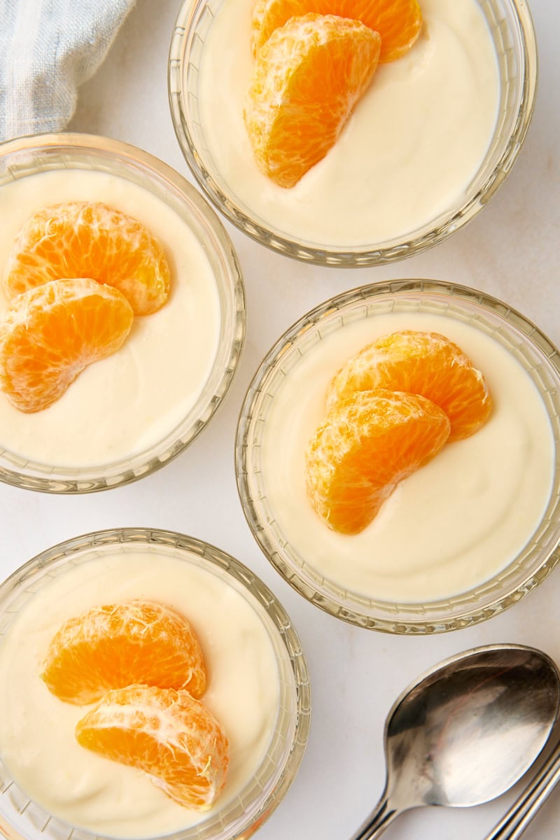 overhead view of four servings of ricotta mousse topped with mandarin slices and served in individual glass ramekins