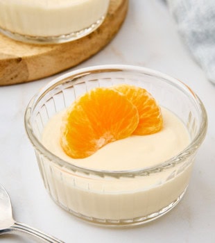 ricotta mousse topped with two mandarin slices and served in a clear glass ramekin