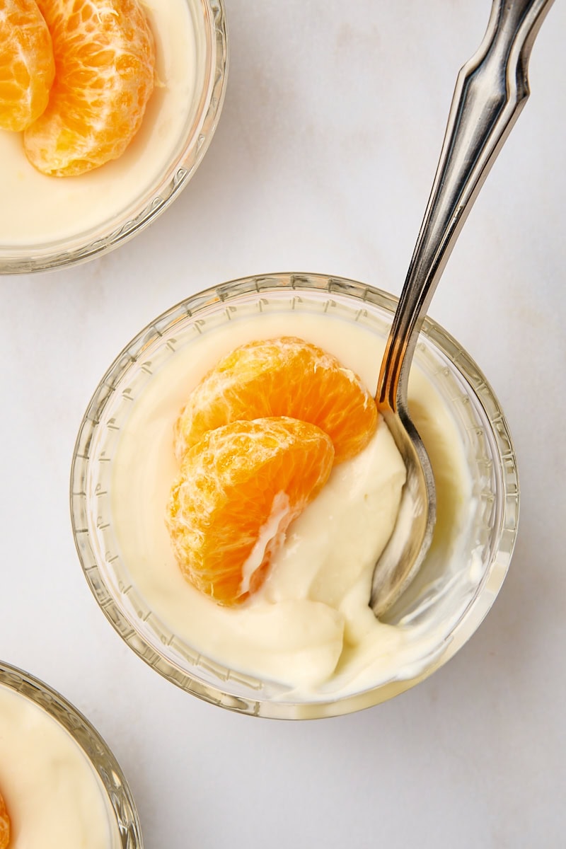 overhead view of ricotta mousse in a clear glass ramekin with a spoon resting inside