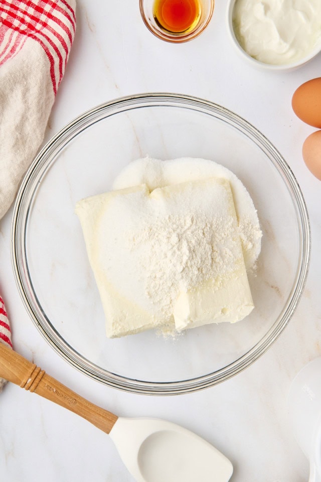 overhead view of cream cheese, sugar, and flour in a glass mixing bowl
