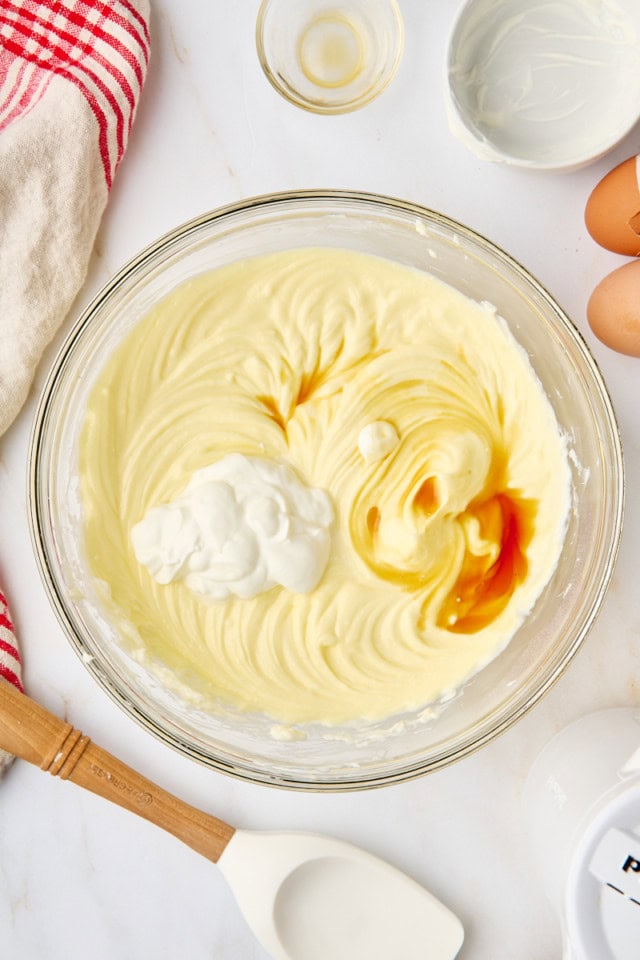 overhead view of sour cream and vanilla added to cheesecake mixture