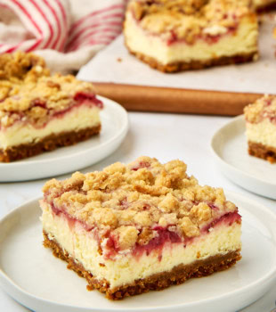 a strawberry cheesecake bar on a white plate with more bars in the background
