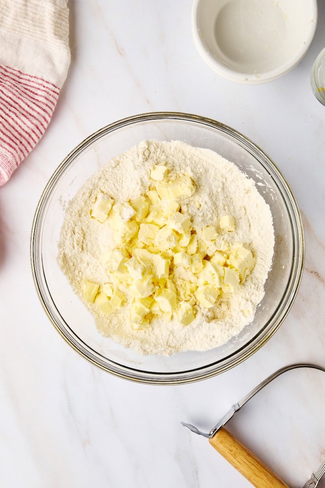 overhead view of cold, cubed butter added to dry ingredients for biscuits