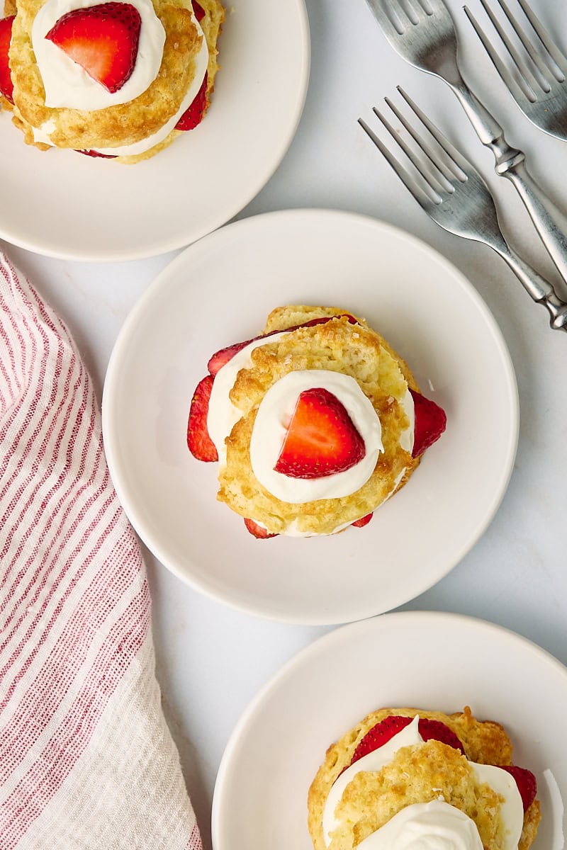overhead view of three assembled strawberry shortcakes on white plates